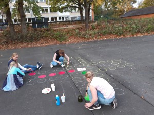 Schüler und Eltern malen "Mensch ärgere Dich nicht auf". 